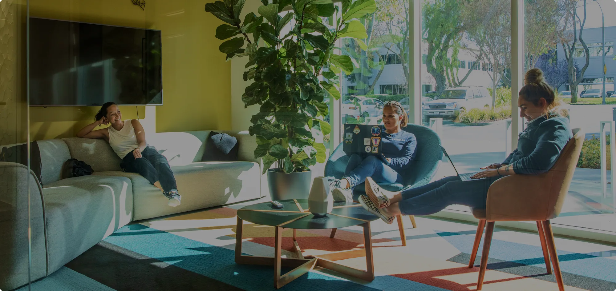 Three women sit in a lounge space